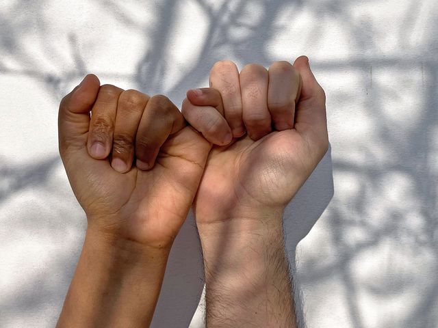 Hände Zwei Hände sind mit den kleinen Fingern ineinander verhakt.